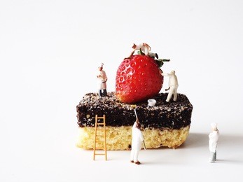 close up miniature people on chocolate cake with fresh strawberry on top,cooking and decoration concept.