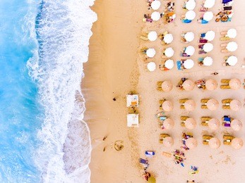 sunbeds and umbrellas bird's eye view on sand beach in greece