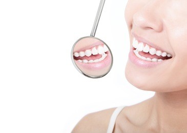 healthy woman teeth and a dentist mouth mirror isolated on white background, model is a asian beauty