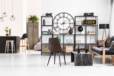 leather chair standing next to an industrial table with beer bottles on it in manly flat interior with open living room