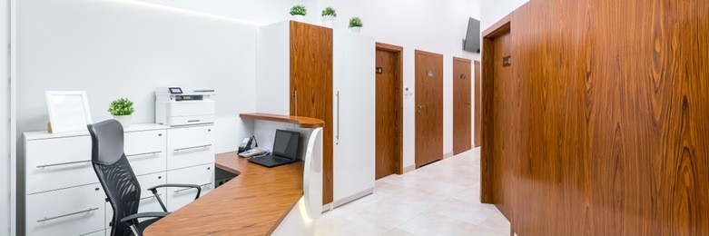 reception of modern, private clinic with wooden desk, panorama