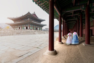 asian korean woman dressed hanbok in traditional dress walking in gyeongbokgung palace in seoul, south korea.