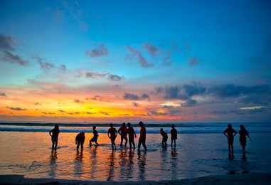 silhouettes of young people at famous sunset beach in kuta, bali, indonesia