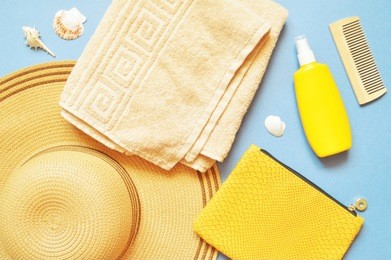 women's sun hat, beige towel, yellow cosmetic bag, sunscreen bottle and seashells. summer holiday, beach relaxation. flat lay composition. top view photo with many items