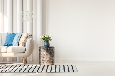 white sofa with colorful cushions standing next to an empty, white wall in a living room interior