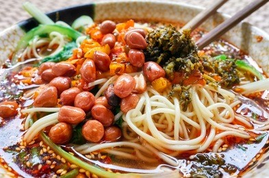 spicy noodle soup with vegetables, herbs, peanuts and coriander, popular in yunnan province, shallow depth of field, china.