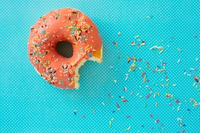 pink donut with colorful icing on a turquoise background. minimal concept. candy shop series. glazed donut.