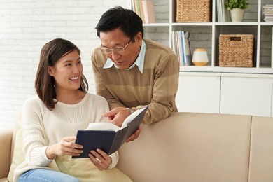 cheerful father and daughter looking at old photos in album