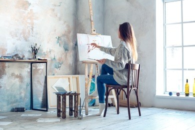young woman artist painting at home creative painting back view