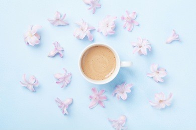 coffee and pink flowers on blue pastel background top view. creative and fashion composition. flat lay style.