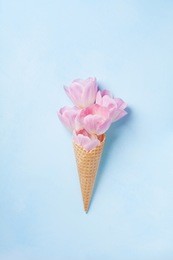 ice cream of pink tulip flowers in waffle cone on blue table top view in flat lay style. 