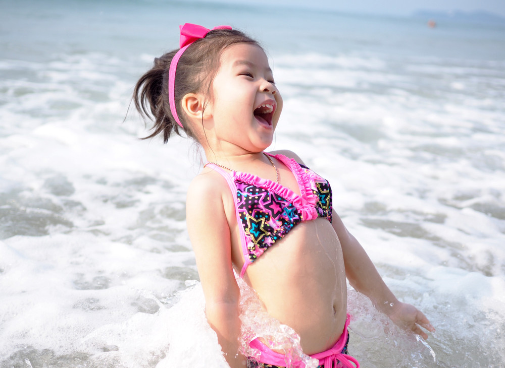 happy smiling asian little girl on beach summer vacation at the day time and sea background       