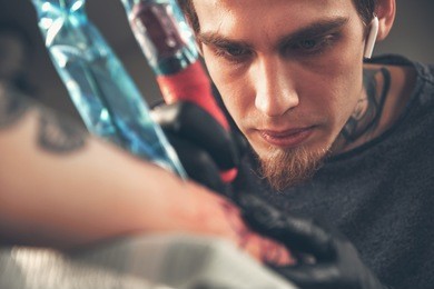 a young guy, beats a tattoo on the hand of the girl in a tattoo parlor, rotary tattoo machine, black ink, lens flare, close up