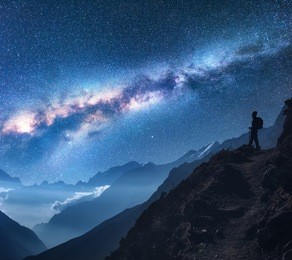 space with milky way, girl and mountains. silhouette of standing woman on the mountain peak, mountains and starry sky at night in nepal. sky with stars. trekking. night landscape with bright milky way
