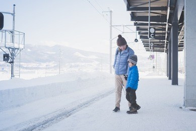 asian mother and son waiting express train on railway station platform,winter travel concept