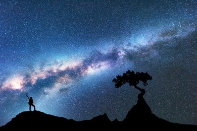 milky way, silhouette of woman and tree growing from the rock on the mountain at night. space background with starry sky, beautiful galaxy and girl. blue milky way, tree and woman. universe. adventure