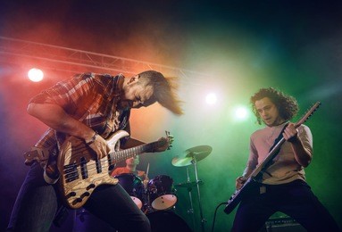 rock band performs on stage. guitarist, bass guitar and drums. the guitarist plays solo.