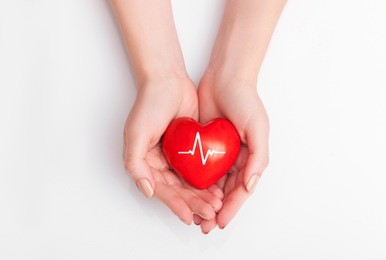 people health concept - close up of woman's cupped hands showing red heart with heart beat.