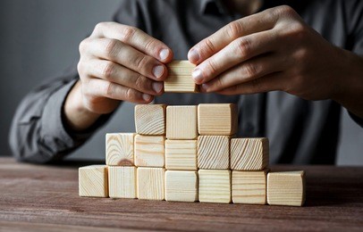 businessman building a pyramid with empty wooden cubes. concept of business hierarchy and business strategy.