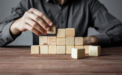 closeup of businessman making a pyramid with empty wooden cubes. concept of business hierarchy and business strategy.