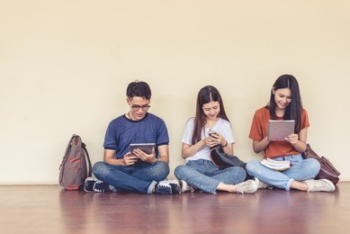 group of asian college student using tablet and mobile phone outside classroom. happiness and education learning concept. back to school concept. teen and people theme. outdoors and technology theme.