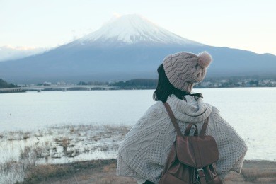 asian woman tourist is traveling into with fuji mountain, lake kawaguchiko in japan during winter.