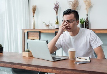 asia casual man cover face with hand upset from work in front of laptop computer in coffee shop,stress emotion concept,work outside office,work at home