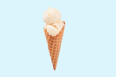 vanilla ice cream cone on blue faded pastel color background. vanilla ice cream in wafer cup.