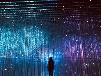 a picture of a lady facing the chains hanging in the ceiling, with a colourful background.