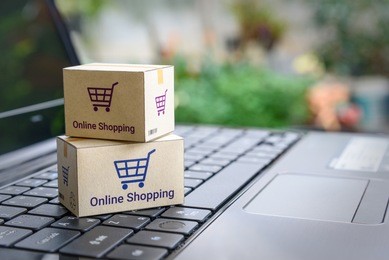 online shopping / ecommerce and delivery service concept : paper cartons with a shopping cart or trolley logo on a laptop keyboard, depicts customers order things from retailer sites via the internet.
