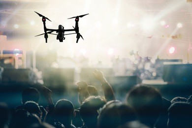 closeup silhouette of drone flying for taking video of concert crowd and music fanclub with show hand action which follow up the songer at the front of stage, musical and concert concept