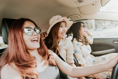 group of three happy asian girl best friends traveler laughing and smiling in car during a road trip to vacation.