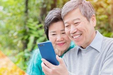 old couple use phone happily in the park
