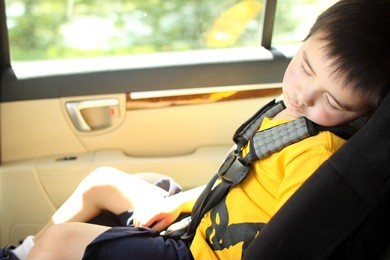 toddler asleep in a child safety seat in a car.