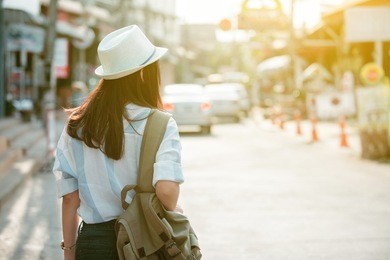 back view of a young woman traveler with a backpack in the city
