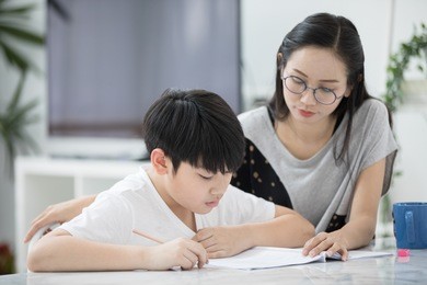 asian boy with mother teaching and learning your homework at home 