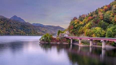 bridge across the lake in autumn  with autumn forest on the hill, hokkaido, japan