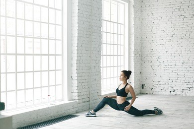 portrait of strong flexible young caucasian sportswoman in trendy sports outfit doing stretching pose, preparing for front splits. attractive fit girl doing exercises to strengthen pelvic health