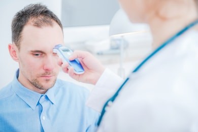 body temperature measurement. female doctor checking temperature using infrared thermometer