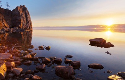 baikal lake on a may evening. spring sunset at the olkhon island. the coastal rocks are reflected in clear water