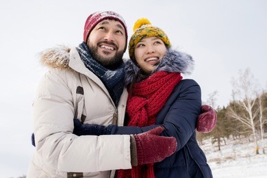 portrait of young asian couple embracing smiling happily enjoying nice winter days outdoors, copy space