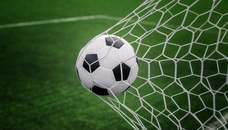soccer ball on goal with net and green background, this photo can use for football, sport, goal, score, shoot and target of business concept
