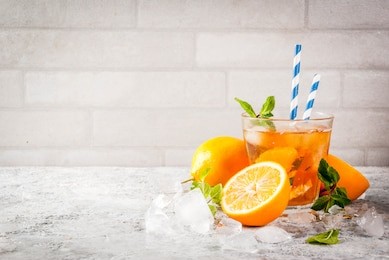 cold summer drink. iced tea with lemon and mint, on grey stone background.  copy space