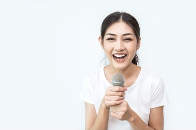 pretty asian girl with the microphone in her hand isolated on white background, closeup portrait of asian woman singing a song. music and education concept