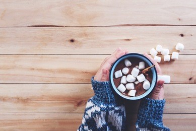 a cup of hot chocolate with marshmallow in women hands