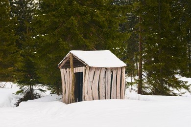 wooden shed in the woods covered with thick layer of snow in winter

