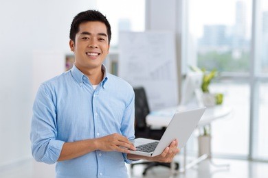 happy young asian software developer with laptop in his hands