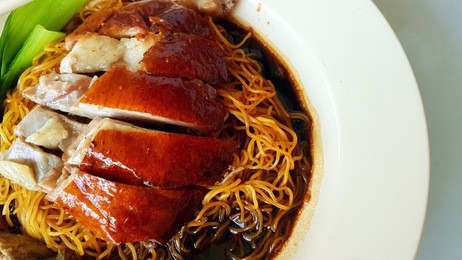 chinese hong kong authentic crispy roasted duck noodles with dark soy sauce and steamed vegetables