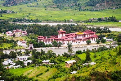 view of punakha dzong with green rice paddy, punakha, bhutan