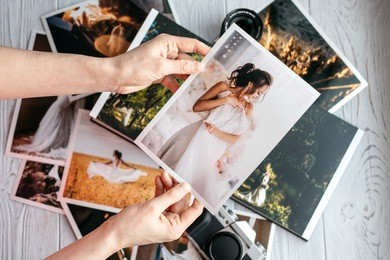 printed wedding photos with the bride and groom, a vintage black camera and woman hands with photo